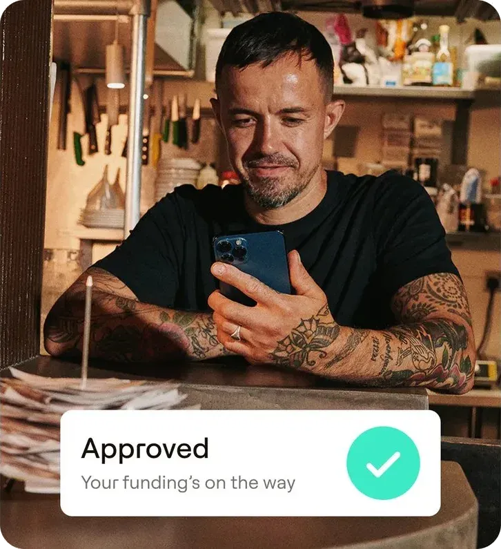 A business owner on his phone with an approved funding notice